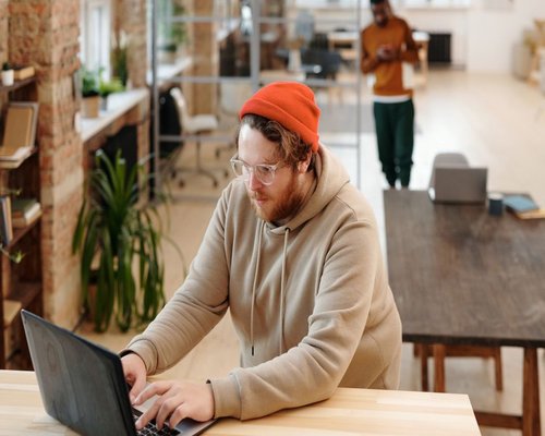 Person typing on a laptop at a bright coworking space